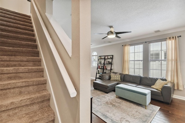 living room with hardwood / wood-style flooring, ceiling fan, crown molding, and a textured ceiling