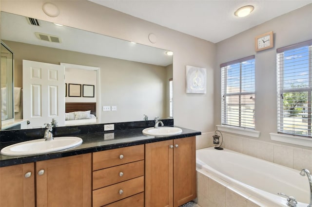 bathroom featuring vanity and a relaxing tiled tub