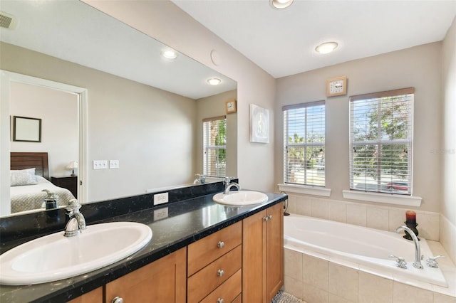 bathroom with vanity and tiled tub