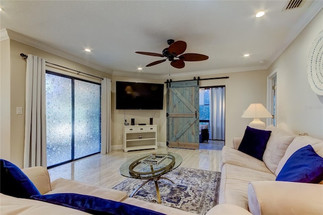 living room featuring ceiling fan, a barn door, and ornamental molding