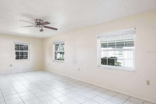 tiled spare room with ceiling fan, a textured ceiling, and a wealth of natural light