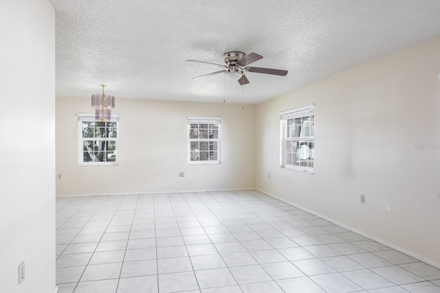 spare room featuring plenty of natural light, light tile patterned flooring, a textured ceiling, and ceiling fan with notable chandelier