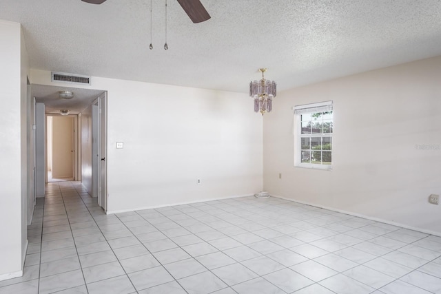 tiled empty room with ceiling fan with notable chandelier and a textured ceiling