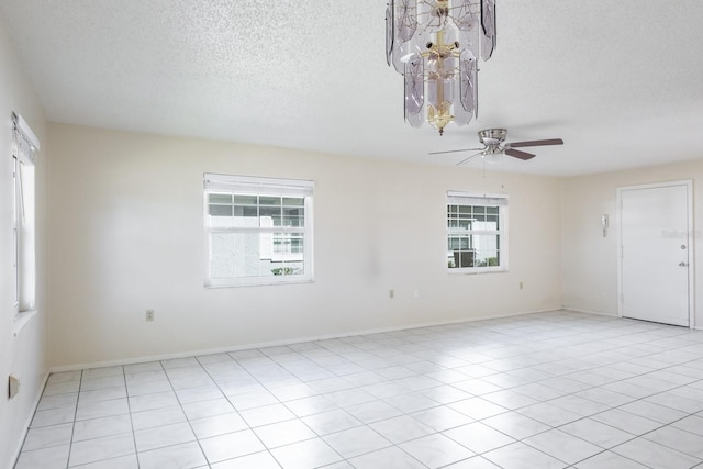 tiled spare room with plenty of natural light, ceiling fan, and a textured ceiling