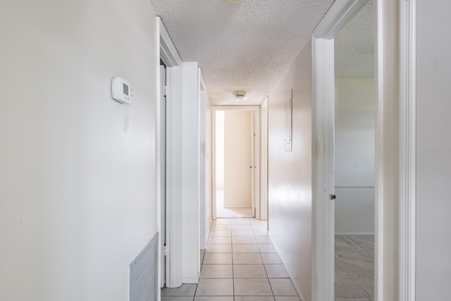 corridor featuring light tile patterned floors and a textured ceiling