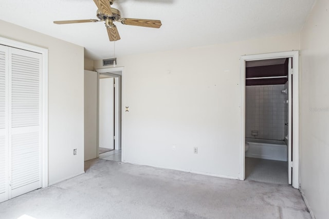 unfurnished bedroom with light carpet, a closet, ensuite bathroom, and ceiling fan