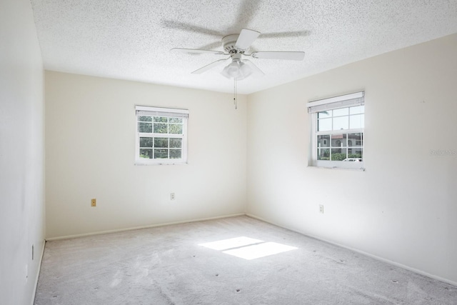 carpeted spare room featuring ceiling fan, plenty of natural light, and a textured ceiling