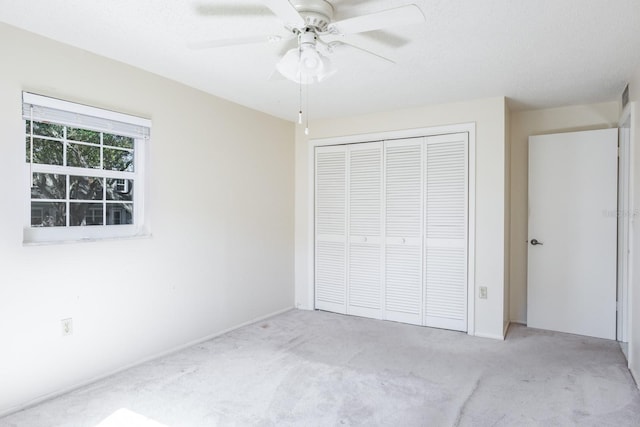 unfurnished bedroom featuring ceiling fan, light carpet, and a closet