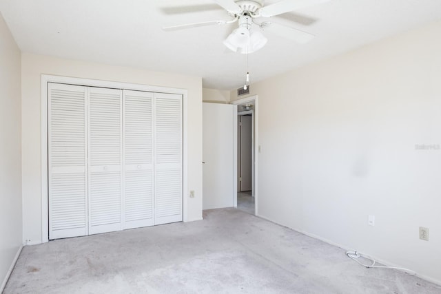 unfurnished bedroom featuring ceiling fan, light colored carpet, and a closet