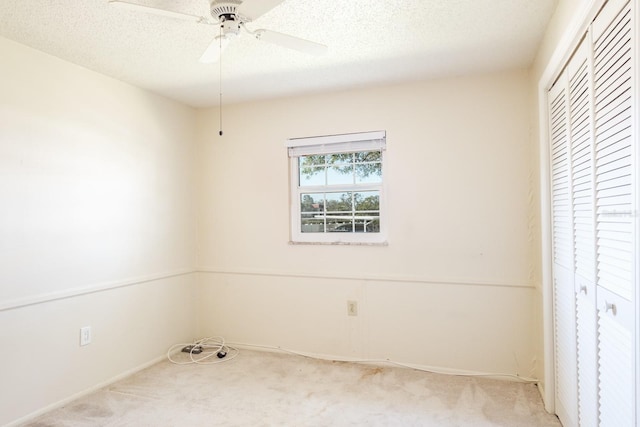 unfurnished bedroom featuring ceiling fan, a closet, light colored carpet, and a textured ceiling