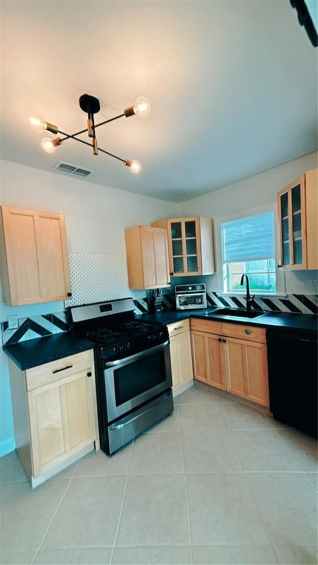 kitchen featuring dishwasher, sink, gas range, light tile patterned floors, and a notable chandelier