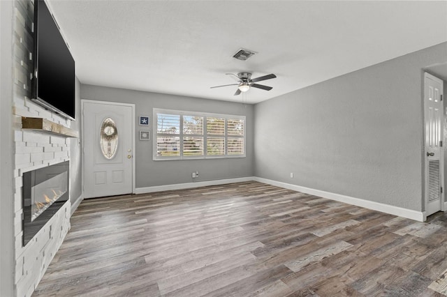 unfurnished living room with a brick fireplace, ceiling fan, and hardwood / wood-style flooring