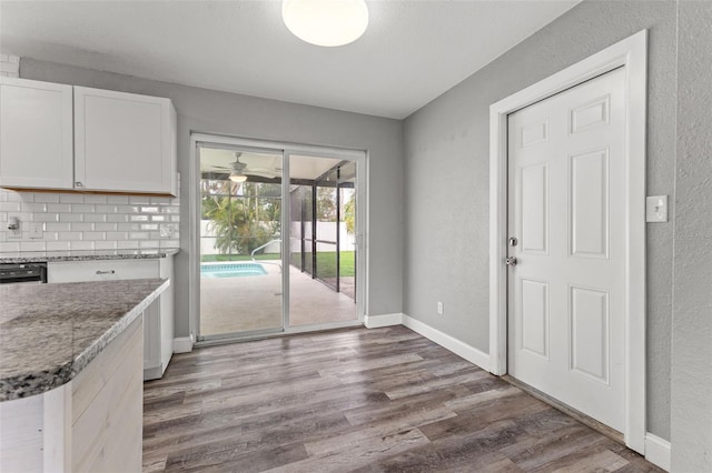 kitchen featuring white cabinets, decorative backsplash, hardwood / wood-style flooring, and dark stone countertops