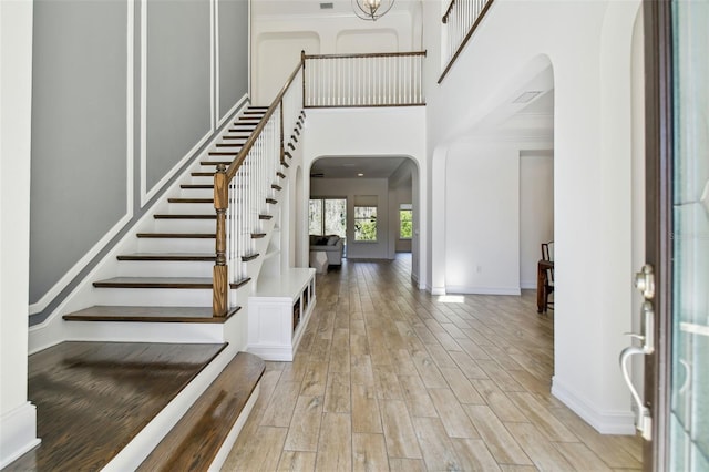 entrance foyer with a high ceiling, ornamental molding, and light wood-type flooring