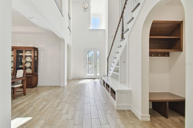 foyer entrance with an inviting chandelier, ornamental molding, and french doors