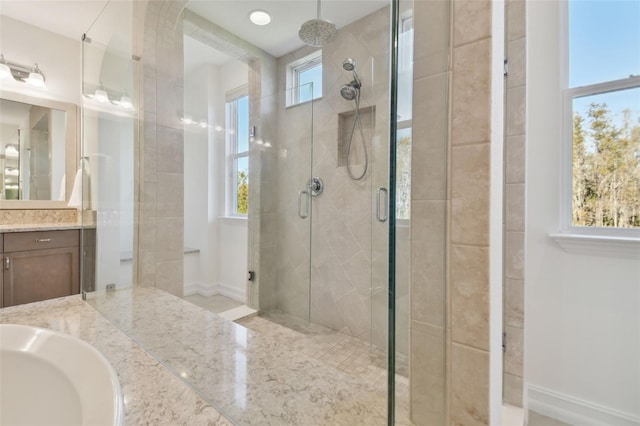 bathroom with a wealth of natural light, walk in shower, and vanity