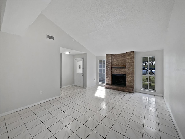 unfurnished living room with a textured ceiling, light tile patterned flooring, a fireplace, and high vaulted ceiling