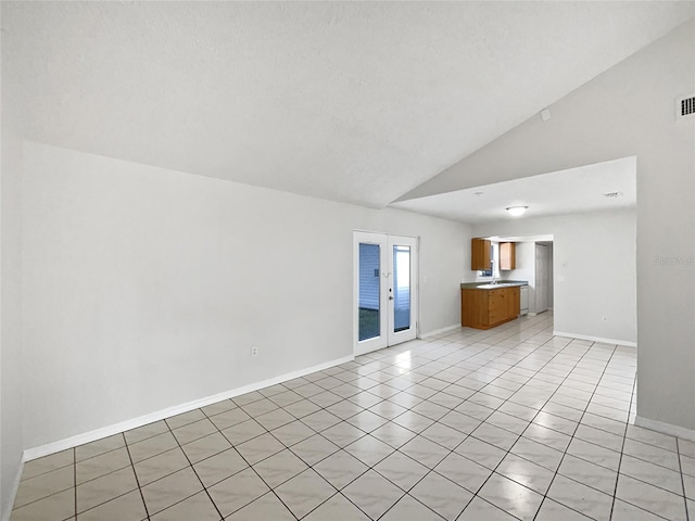 empty room featuring light tile patterned floors, high vaulted ceiling, and french doors