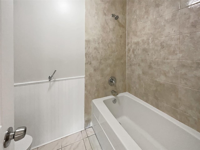 bathroom with tile patterned flooring, tiled shower / bath combo, and toilet