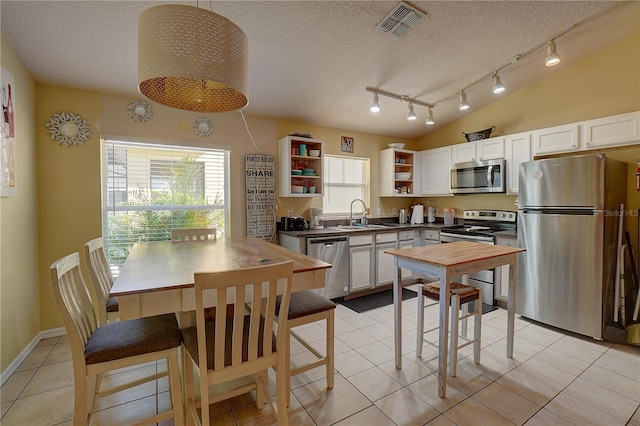 kitchen featuring appliances with stainless steel finishes, a textured ceiling, white cabinetry, and sink