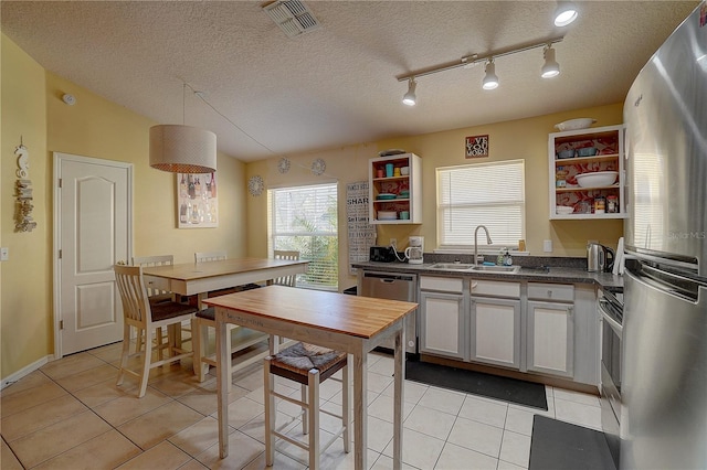 kitchen with white cabinets, sink, light tile patterned floors, a textured ceiling, and stainless steel appliances