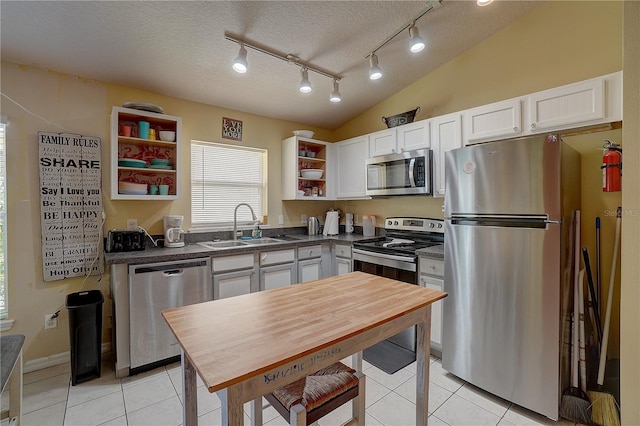 kitchen with lofted ceiling, sink, a textured ceiling, appliances with stainless steel finishes, and white cabinetry