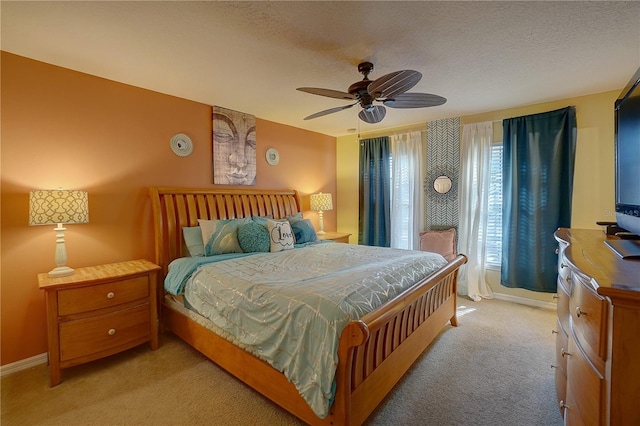 bedroom with ceiling fan, light colored carpet, and a textured ceiling