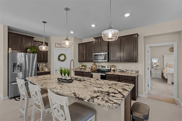 kitchen featuring hanging light fixtures, an island with sink, and stainless steel appliances