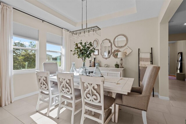 dining space with a raised ceiling and light tile patterned floors