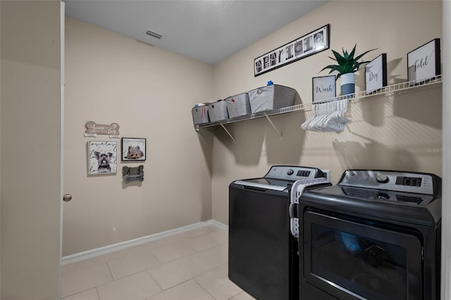 laundry area with washer and clothes dryer and light tile patterned floors