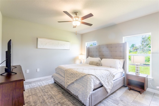 tiled bedroom with ceiling fan and multiple windows