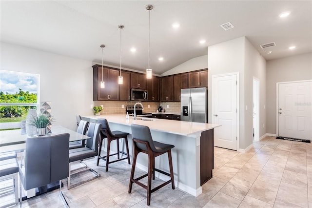 kitchen featuring kitchen peninsula, appliances with stainless steel finishes, dark brown cabinets, hanging light fixtures, and vaulted ceiling