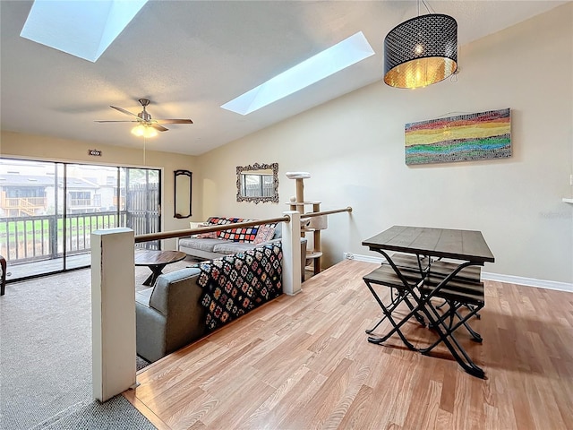 living room with a skylight, wood finished floors, lofted ceiling, baseboards, and ceiling fan