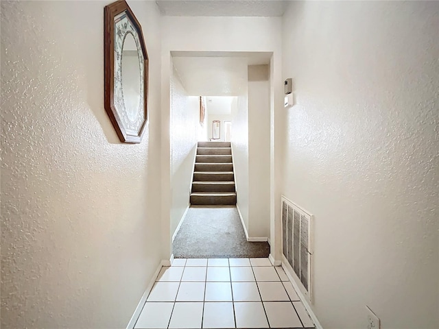 hallway featuring stairs, baseboards, carpet flooring, and tile patterned flooring
