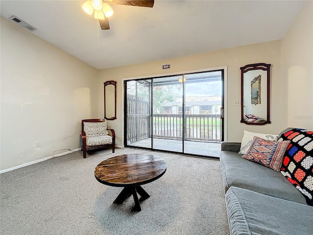 carpeted living area with ceiling fan, baseboards, and a textured ceiling