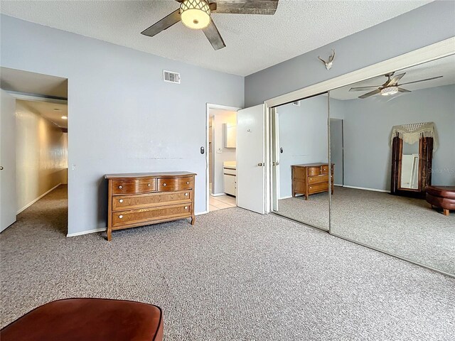 bedroom featuring light carpet, a closet, a ceiling fan, and a textured ceiling
