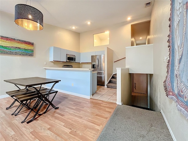 kitchen with appliances with stainless steel finishes, light wood-type flooring, baseboards, light countertops, and recessed lighting