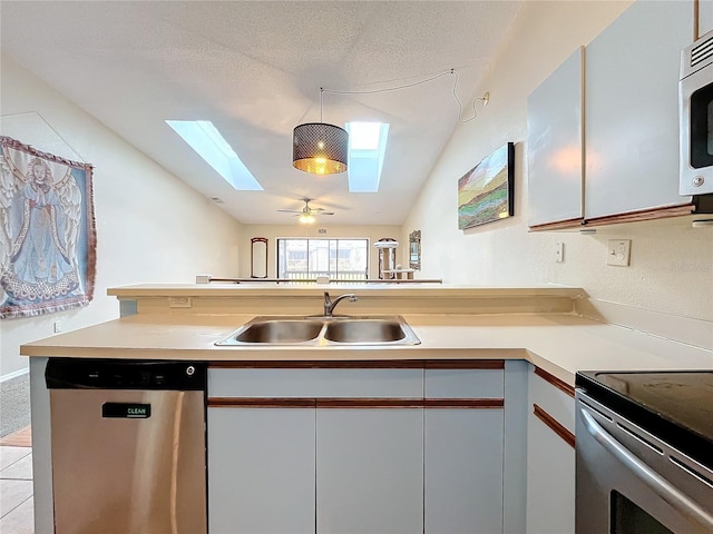 kitchen with stainless steel appliances, a skylight, a sink, vaulted ceiling, and light countertops