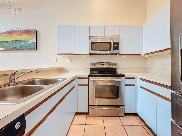 kitchen featuring appliances with stainless steel finishes, a sink, light countertops, light tile patterned floors, and white cabinetry