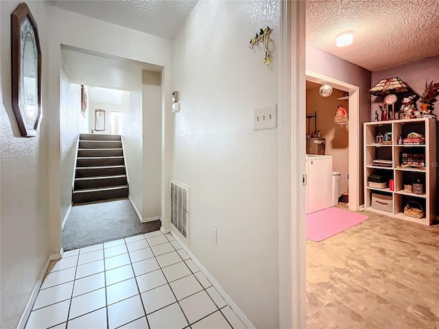 hallway with a textured ceiling, stairway, and baseboards