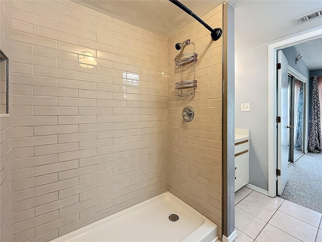 bathroom with a textured ceiling, tile patterned floors, a tile shower, and baseboards