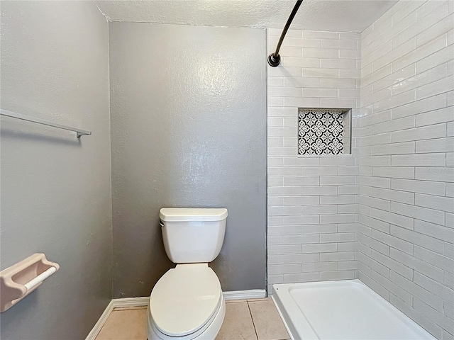 full bathroom with a shower stall, toilet, tile patterned floors, a textured ceiling, and baseboards