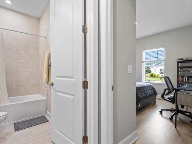 bathroom with toilet and tiled shower / bath