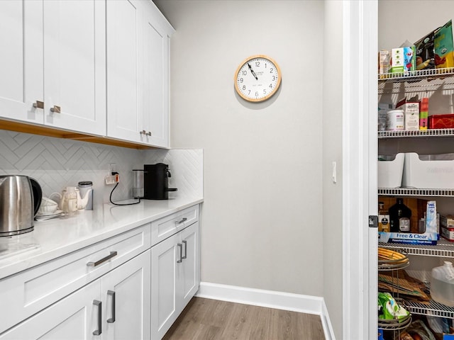 bar featuring white cabinets, backsplash, and light hardwood / wood-style flooring