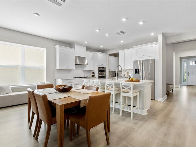 dining room with plenty of natural light, light hardwood / wood-style floors, and sink