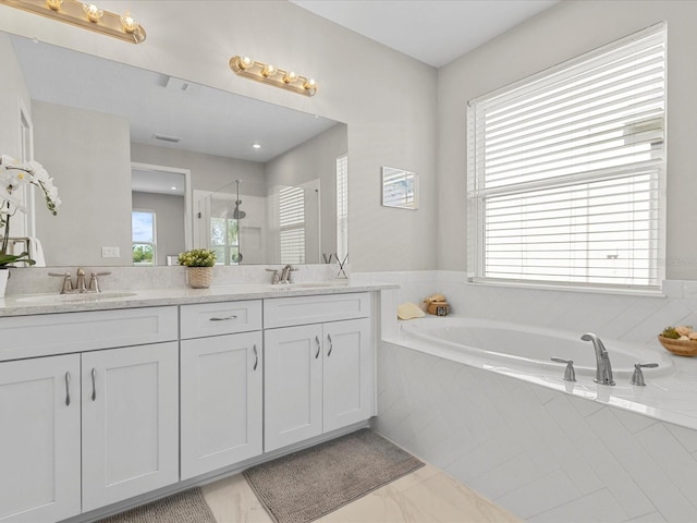 bathroom featuring vanity, separate shower and tub, and a wealth of natural light