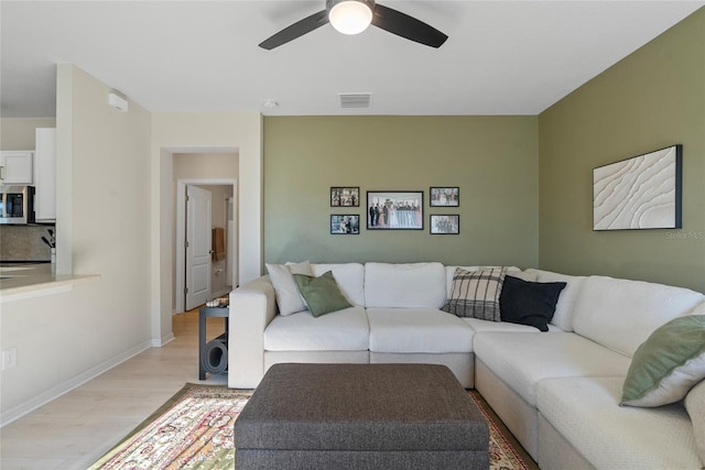 living room with ceiling fan and light wood-type flooring