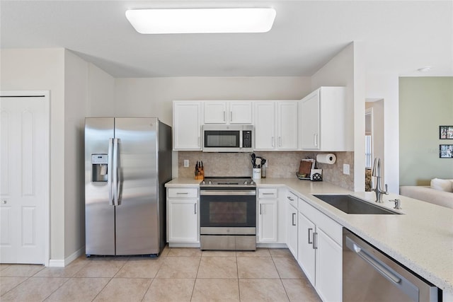 kitchen featuring white cabinets, sink, light tile patterned floors, appliances with stainless steel finishes, and tasteful backsplash