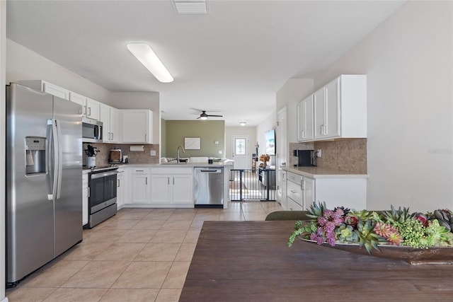 kitchen with white cabinetry, sink, stainless steel appliances, kitchen peninsula, and decorative backsplash