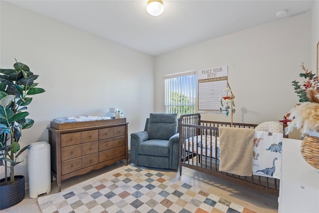 bedroom featuring light hardwood / wood-style floors and a nursery area